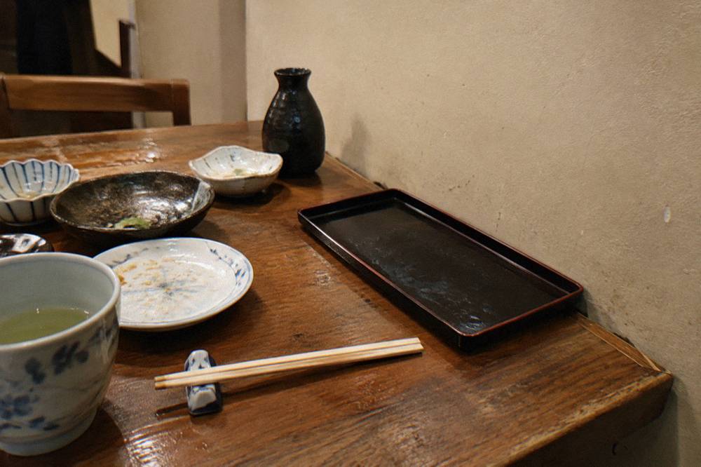 A neat stack of yen banknotes and coins resting on a small black payment tray at a restaurant counter