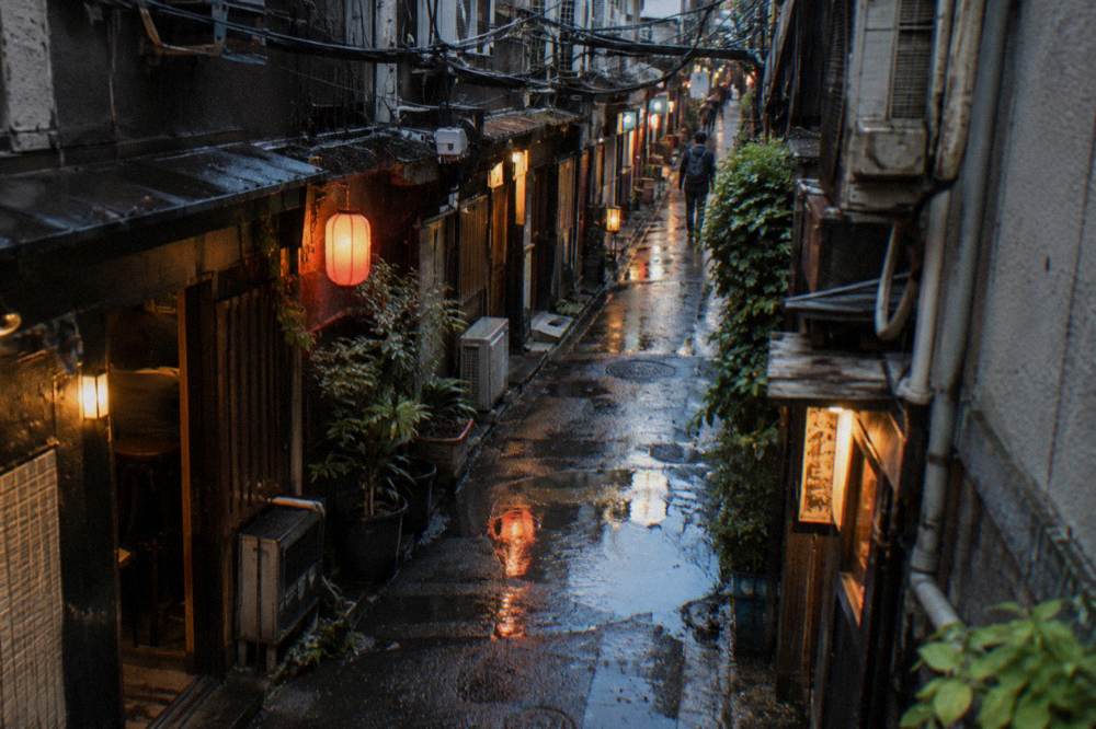 A narrow lantern-lit Golden Gai alley in Shinjuku with small glowing bar entrances on both sides