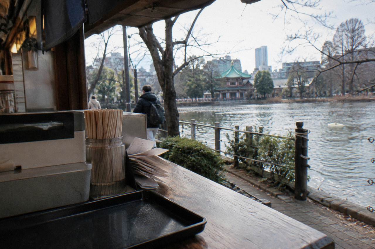 A wooden counter register in a small Tokyo izakaya with a tray of receipts beside it