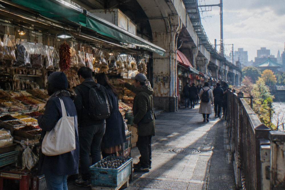 A guide leading a small group between food stalls in a Tokyo market district