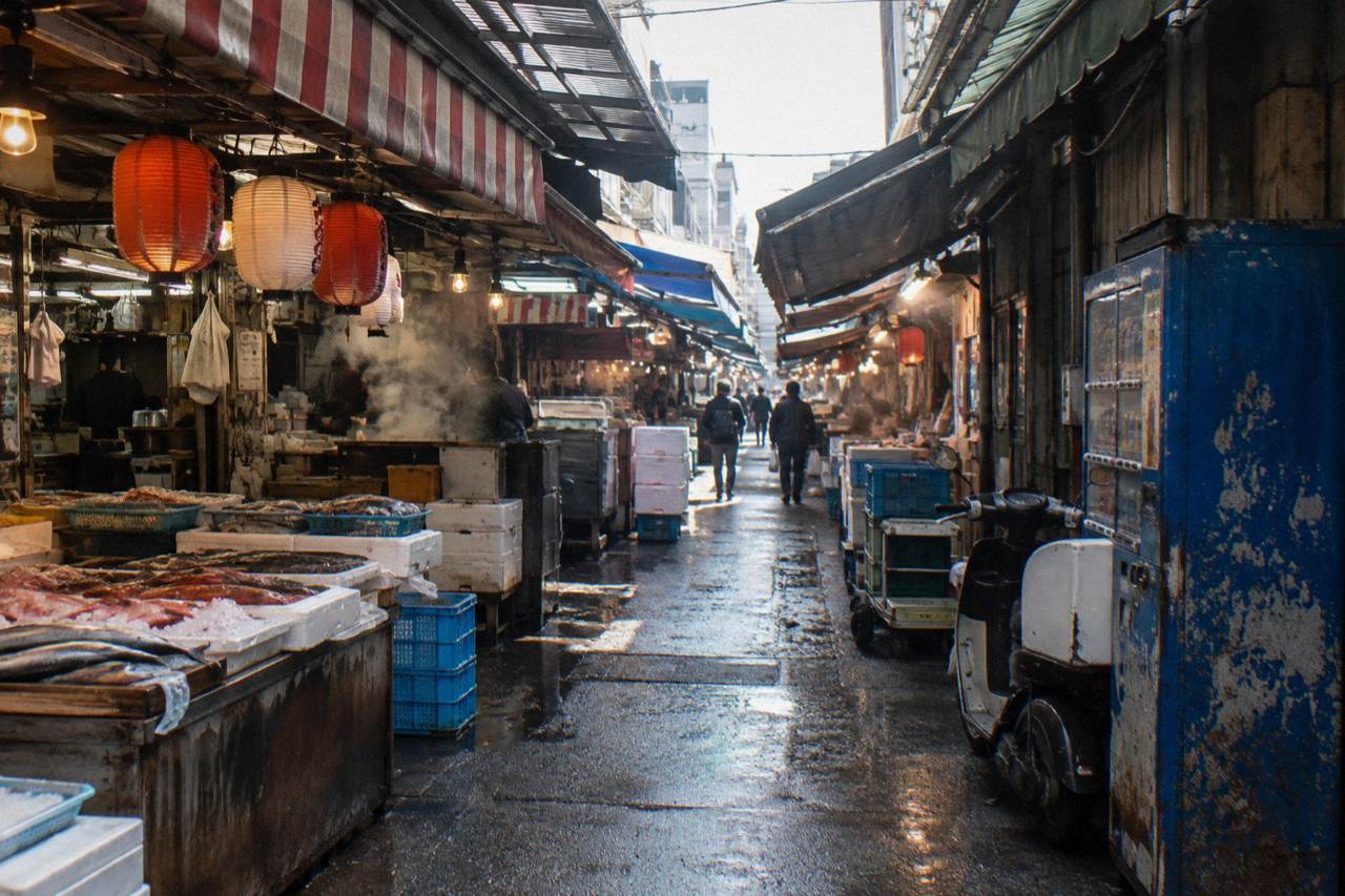 Narrow market lane with seafood stalls and hanging lanterns in Tsukiji Outer Market