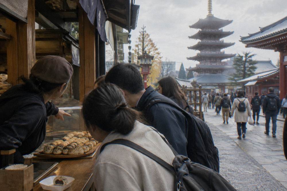 Small group of walkers gathered around a food stall counter while a guide points at displayed dishes