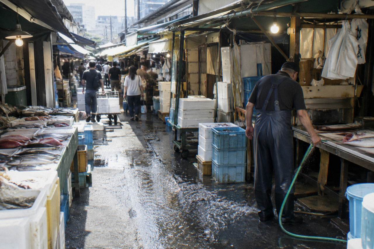 Busy narrow lane of a Tokyo market lined with small seafood stalls and hanging shop signs