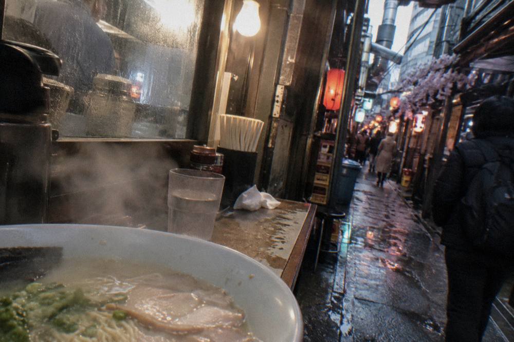 A bowl of creamy white tonkotsu ramen with thin noodles and sliced pork on a counter