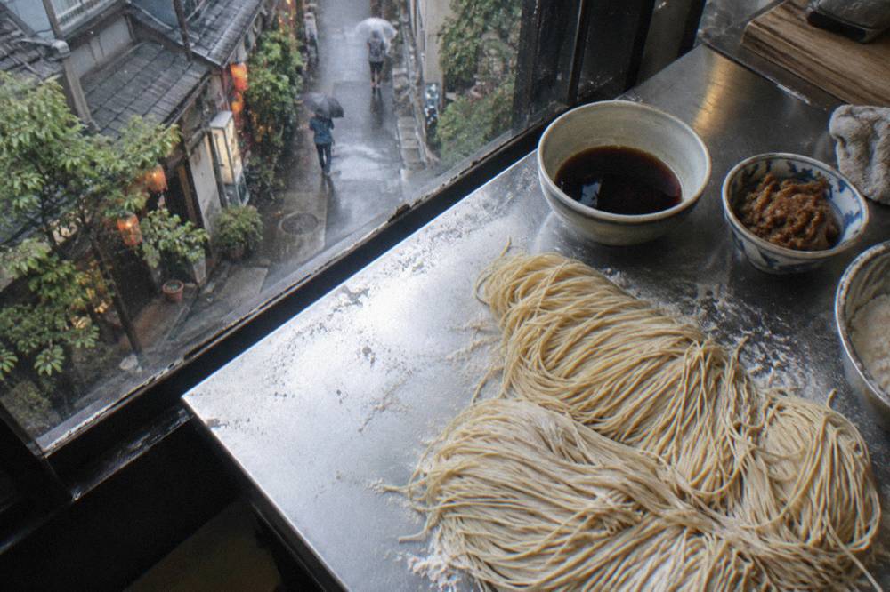Fresh ramen noodles and small bowls of miso paste and soy sauce tare arranged on a cooking class counter