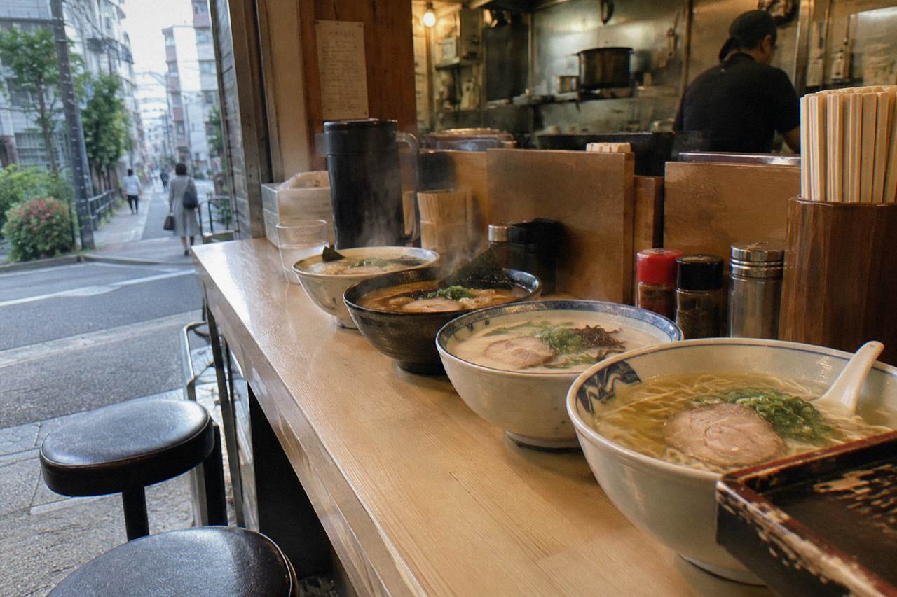Bowls of ramen with different broths lined up on a wooden counter in a small Tokyo shop