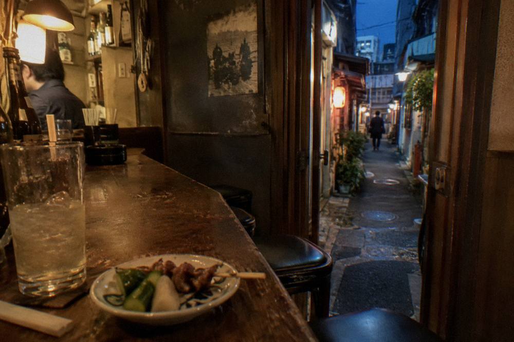 Close view of a compact wooden izakaya counter with grilled skewers and small dishes laid out
