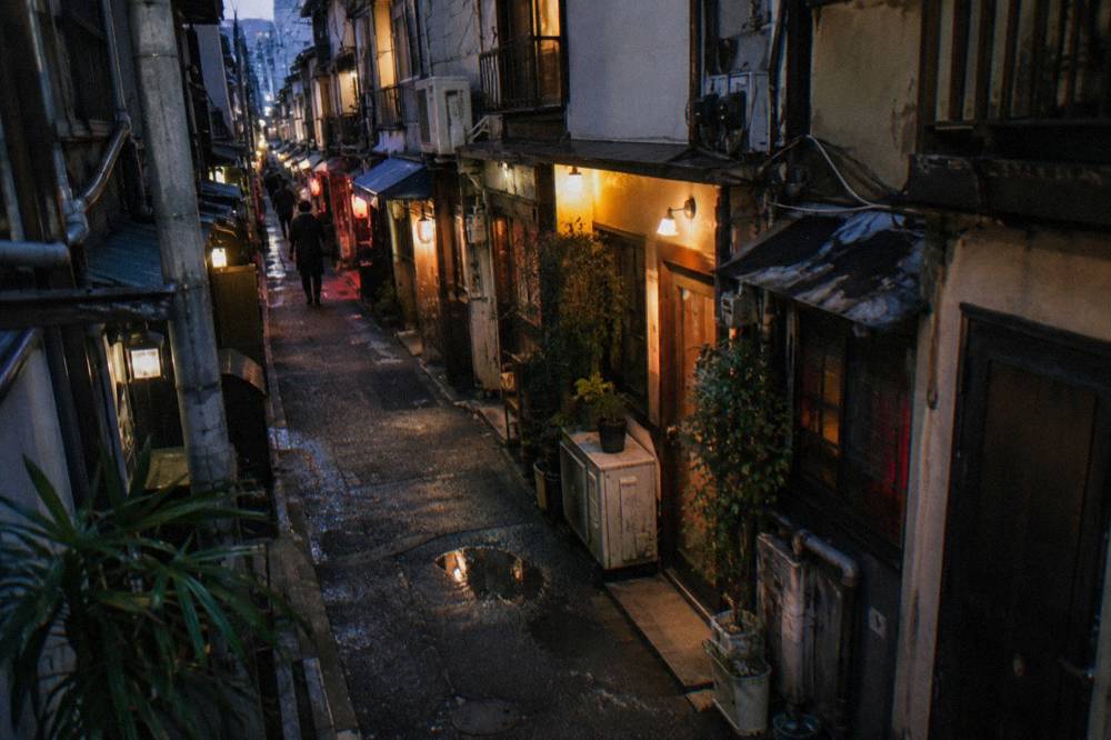 Rows of small lantern-lit bar fronts along a narrow Golden Gai alley at night