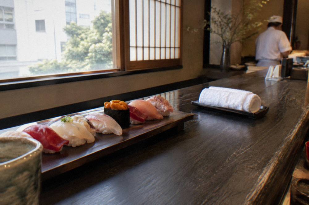 Close view of nigiri sushi pieces arranged along a dark wooden counter