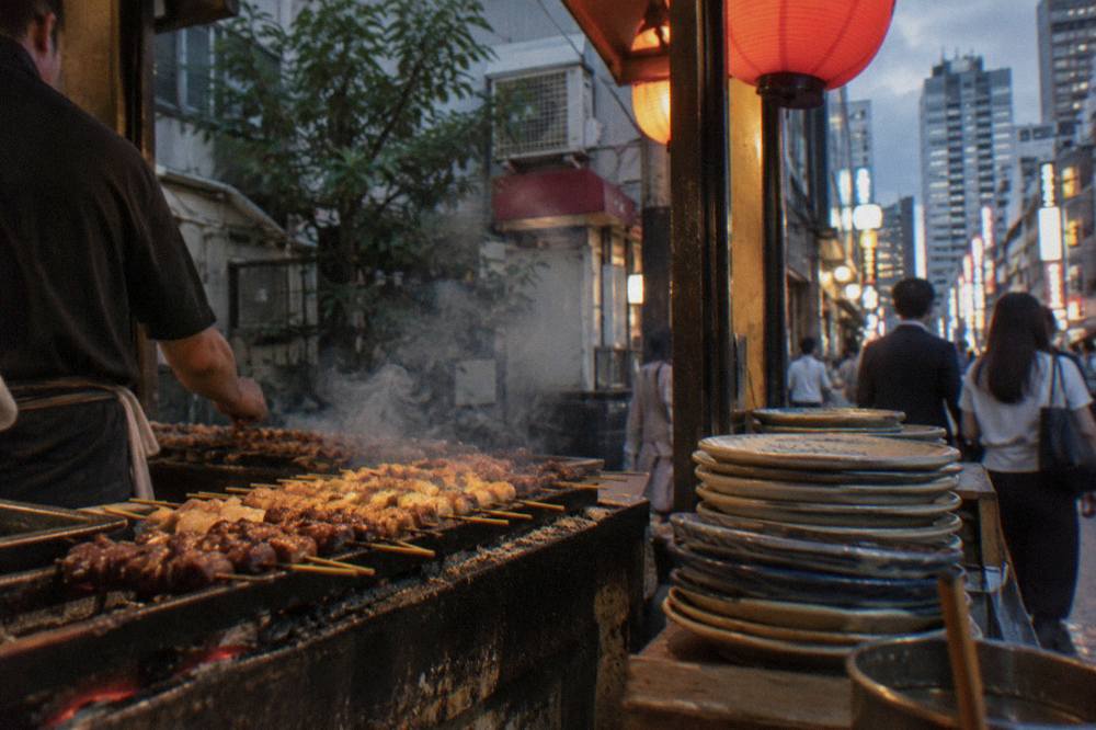 Yakitori skewers grilling over charcoal at a small counter restaurant