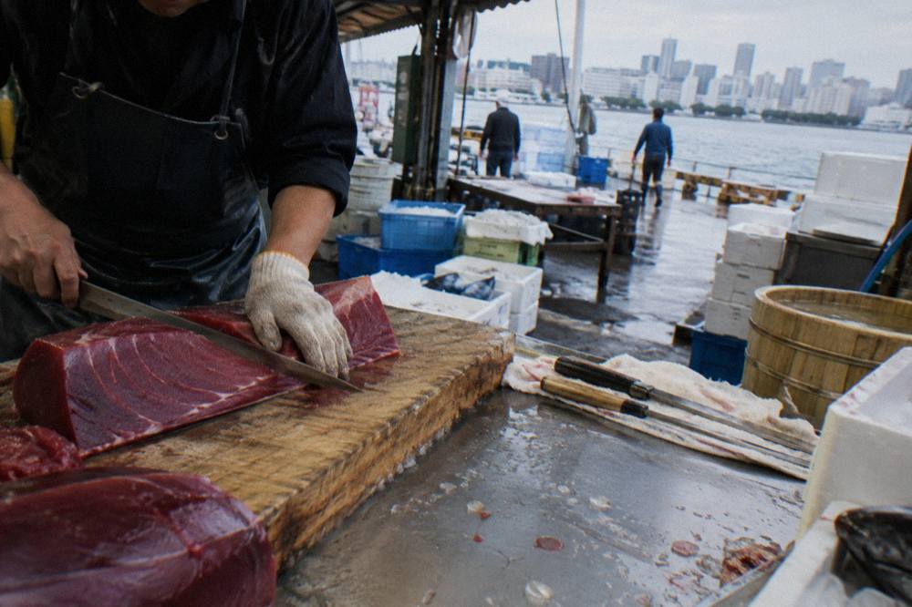 A fresh tuna fillet being sliced at a seafood counter in a Tokyo market