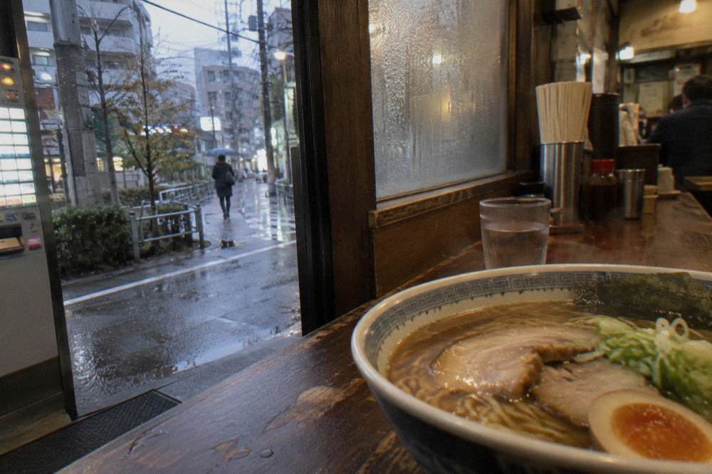 A bowl of ramen with sliced pork and a soft egg on a wooden counter