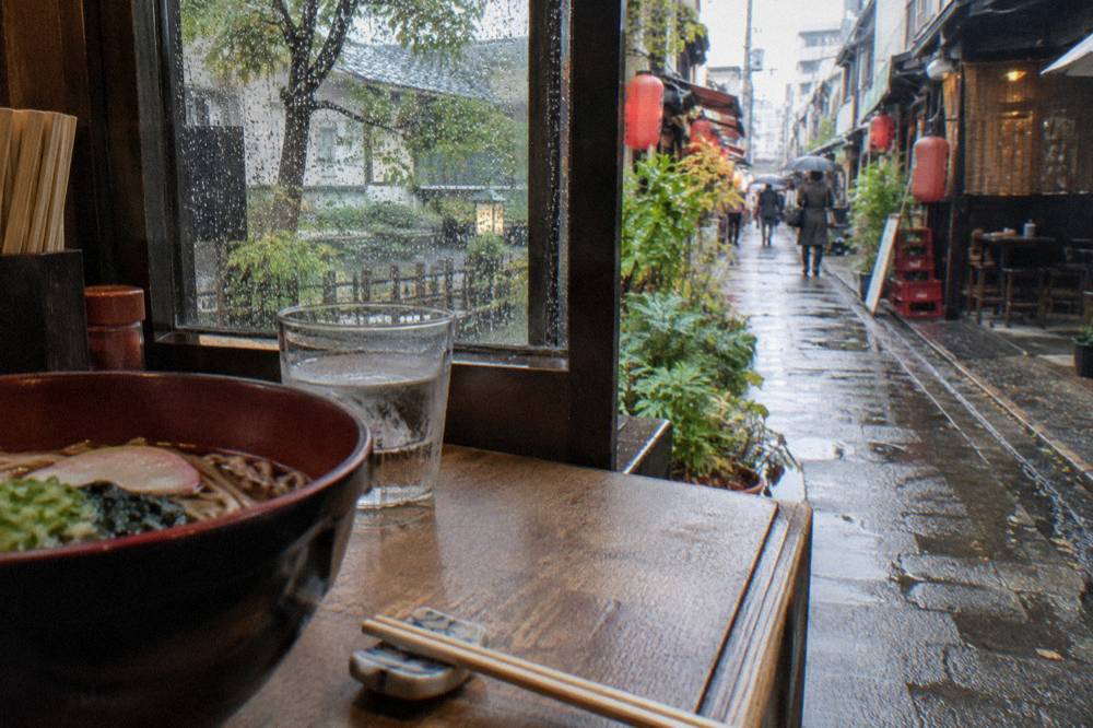 Pair of wooden chopsticks resting on a ceramic holder beside a lacquered bowl on a restaurant table