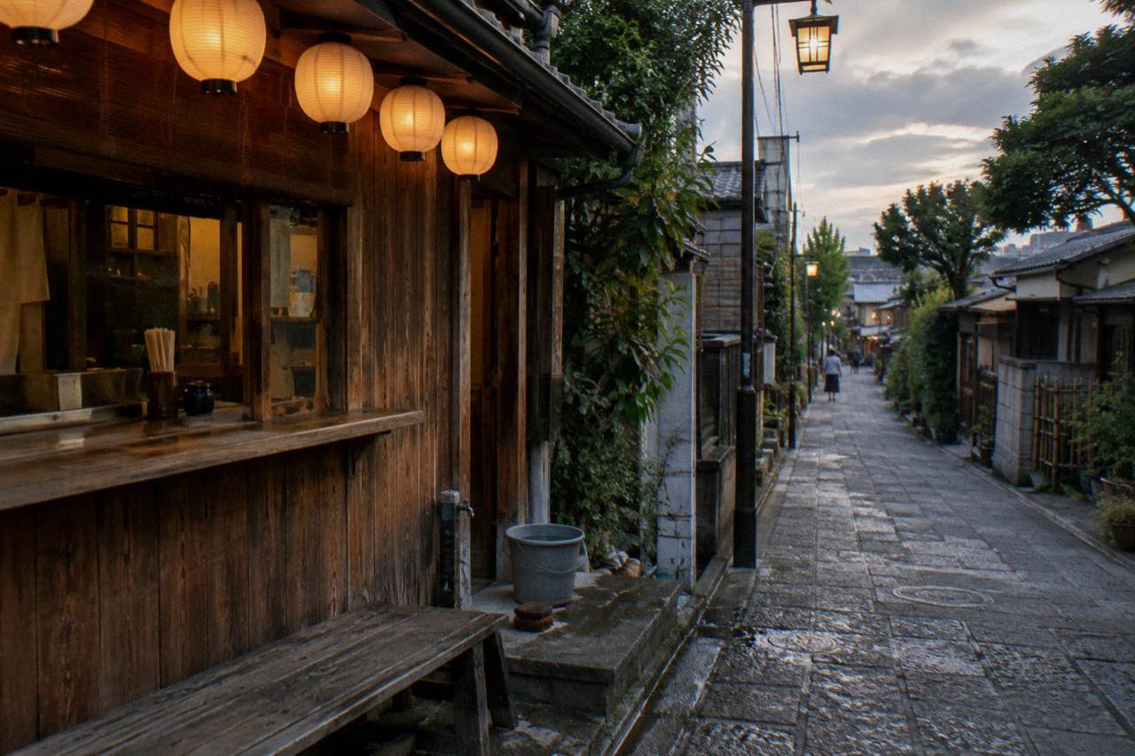 Wooden counter of a small Tokyo restaurant with lanterns glowing above an empty street at dusk