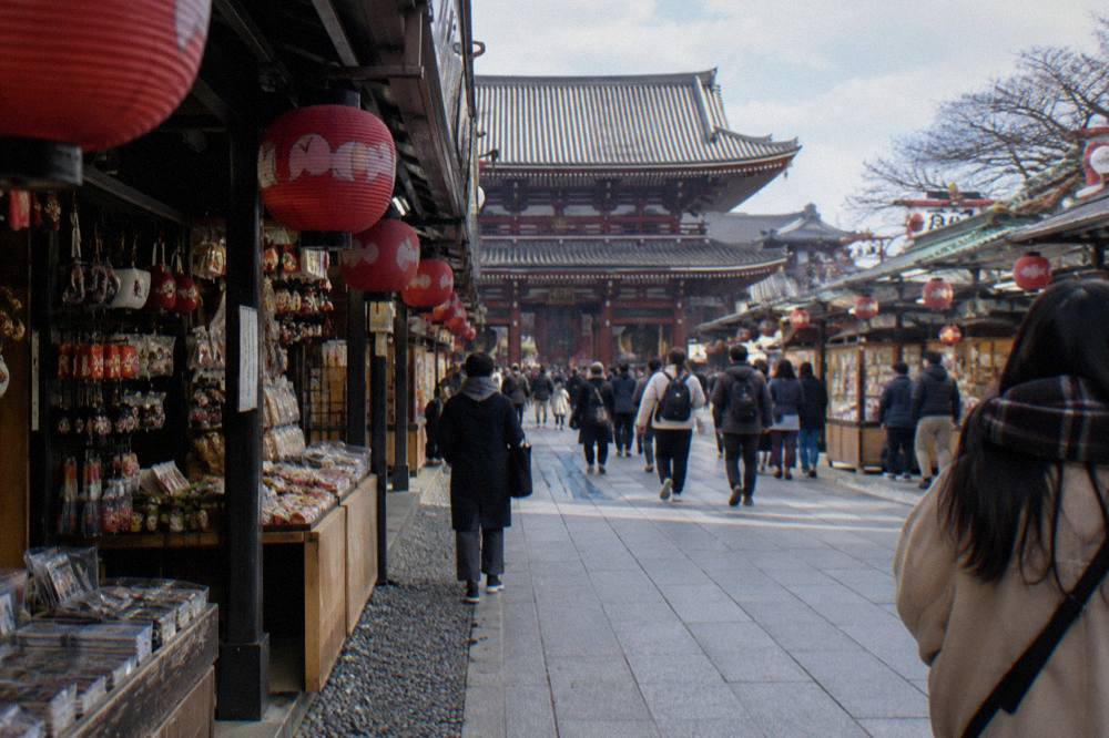 Busy old shopping street with red lanterns and small food stalls in daylight