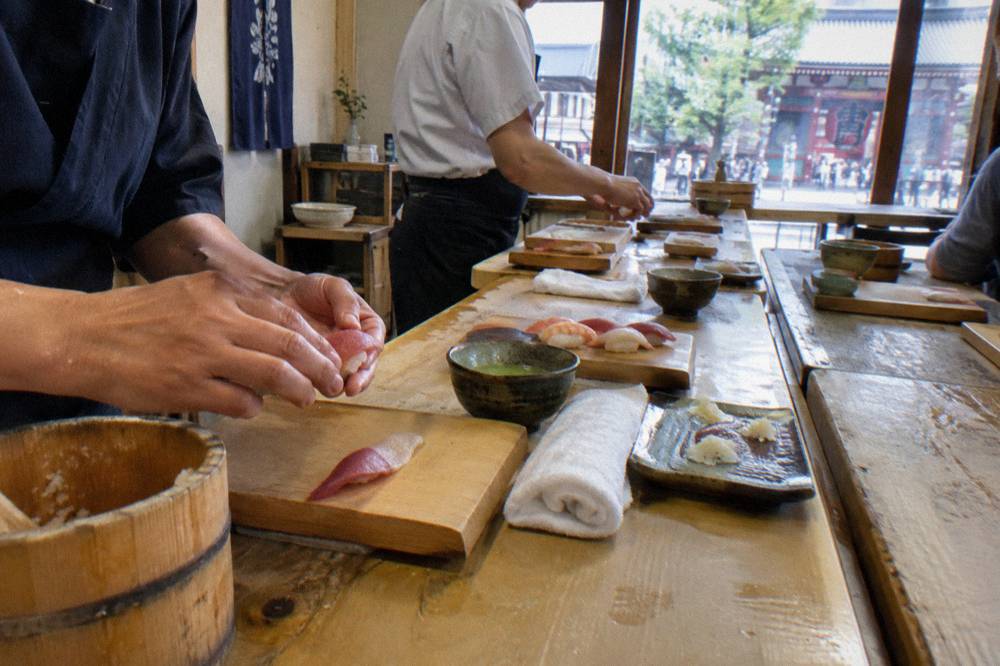 Chef pressing nigiri sushi by hand at a small wooden counter