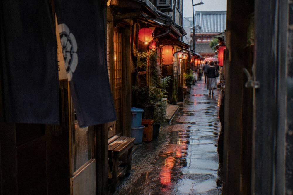 Narrow lantern-lit alley of tiny bars and eateries at night