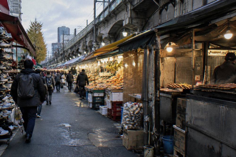Street food stalls lining a covered Tokyo shopping arcade in the evening