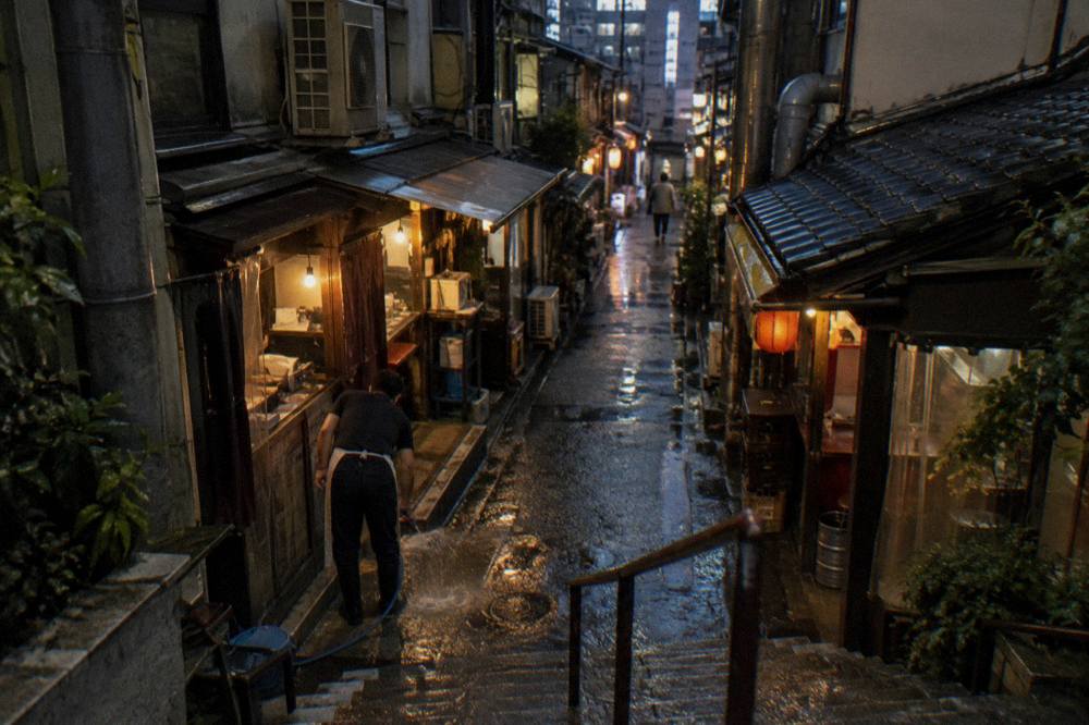 Narrow lantern-lit food alley in Shinjuku at night with small counters on both sides
