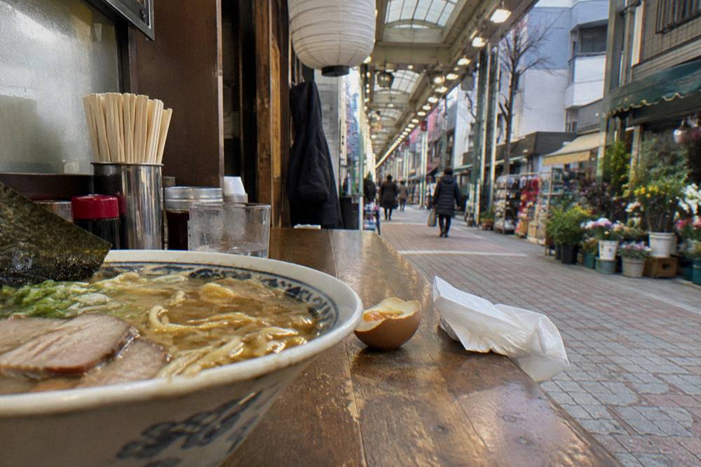 Close view of ramen bowl with broth, sliced pork and noodles on a wooden counter