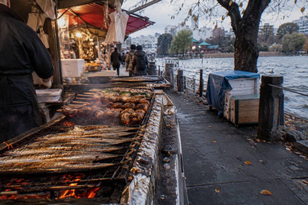 Grilled Pacific saury and mushroom skewers on a market stall counter in autumn
