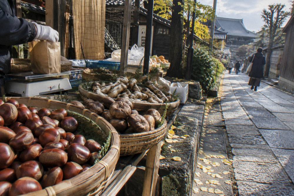 Chestnuts and autumn mushrooms displayed in woven baskets at a Tokyo market stall