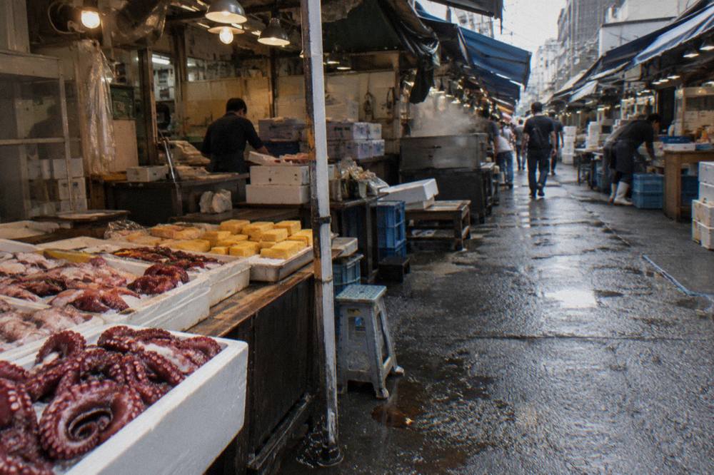 Narrow Tsukiji Outer Market lane lined with small seafood stalls and hanging shop signs