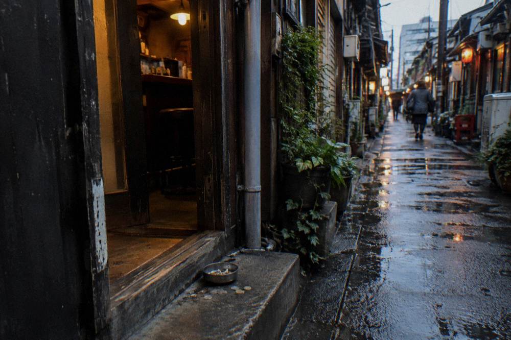 Row of tiny Golden Gai bars with warm light spilling from narrow doorways