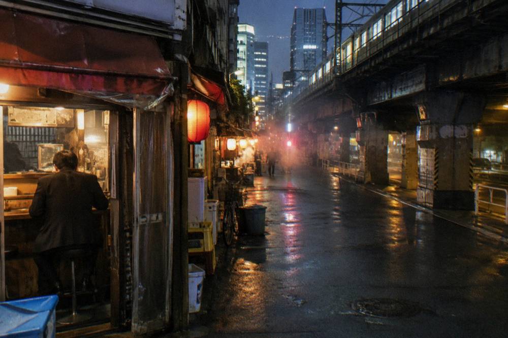 Busy Shinjuku side street at night with lit signage and small eateries