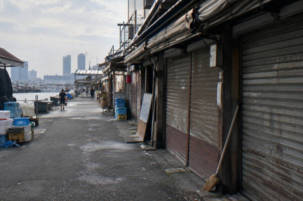 Row of wooden market stalls with folded awnings along a quiet shopping street