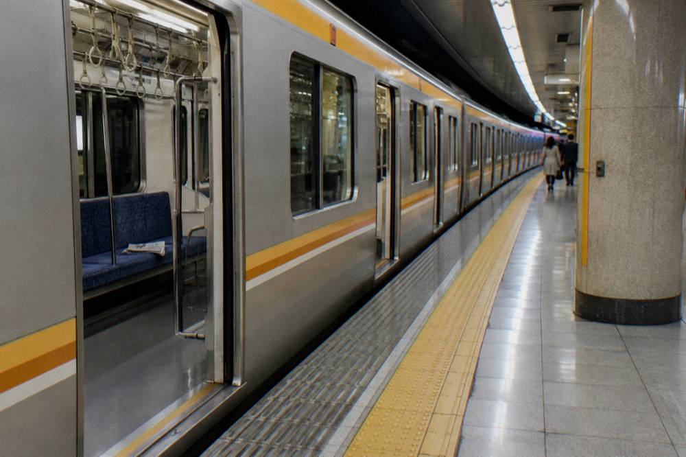 Subway platform with a train arriving beside a station sign in Tokyo