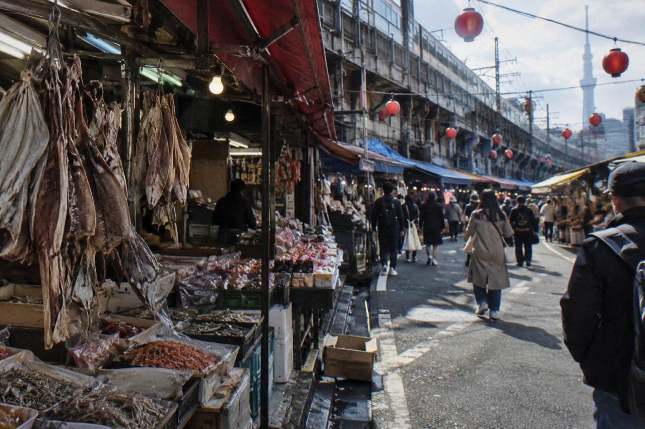 Narrow market lane lined with small food stalls and hanging lanterns in daylight