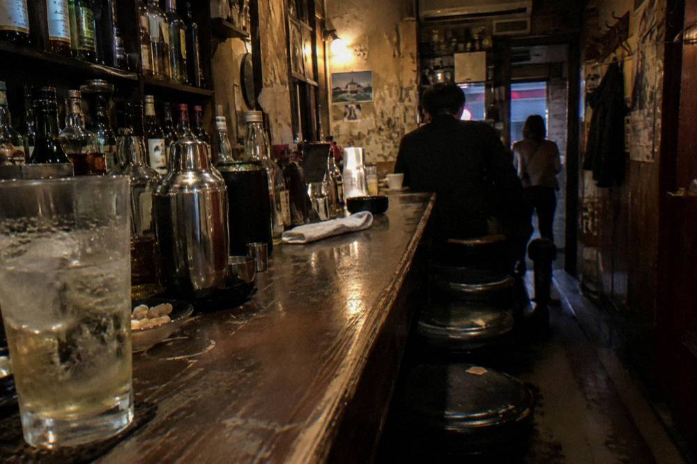 Small bar counter with bottles and glasses lit by warm interior light