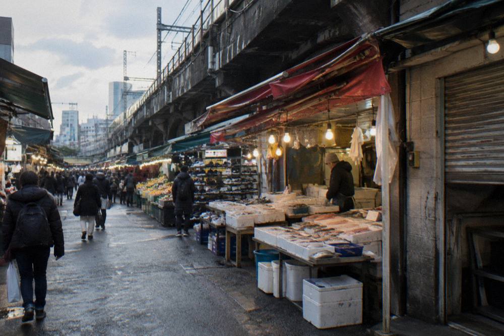 Street food stalls lining a covered Tokyo shopping arcade in the evening
