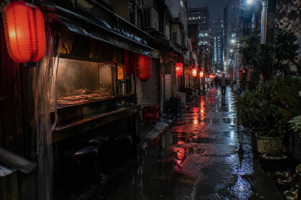 Neon signs and lanterns above a narrow bar street in Shinjuku at night