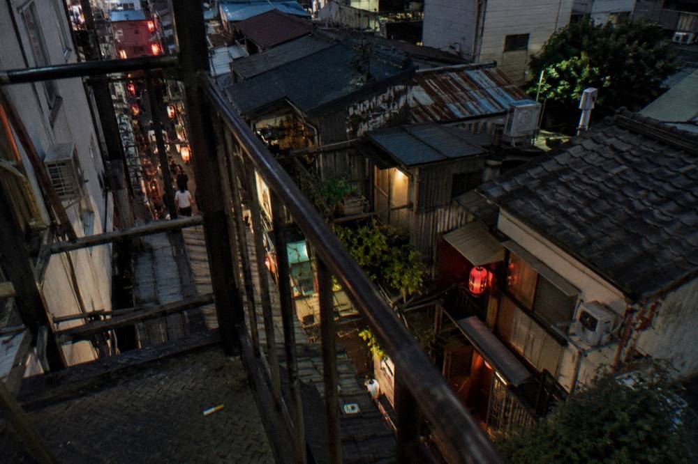 Row of tiny bars with glowing signs in a Golden Gai alley in Shinjuku