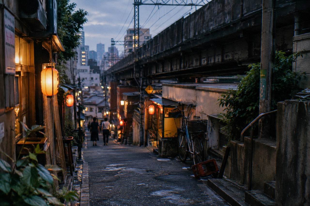 Lanterns glowing above a narrow Tokyo alley of small restaurants at dusk
