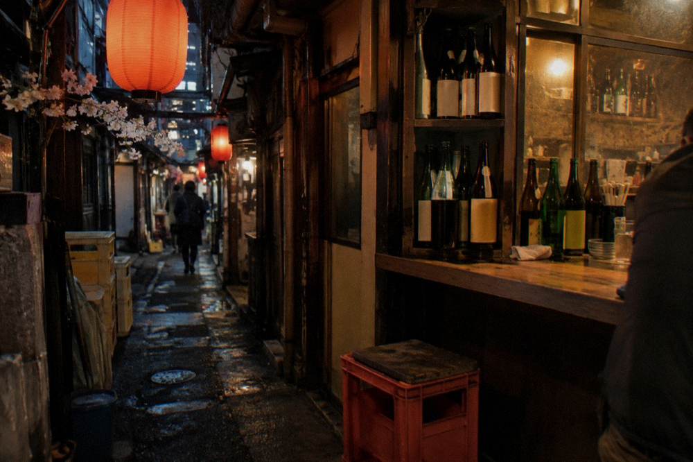 Counter interior with bottles of sake and shochu stacked along a wooden shelf