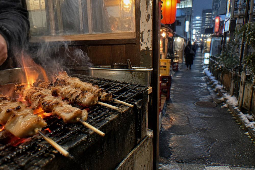 Close view of grilled chicken skewers being turned over glowing charcoal coals