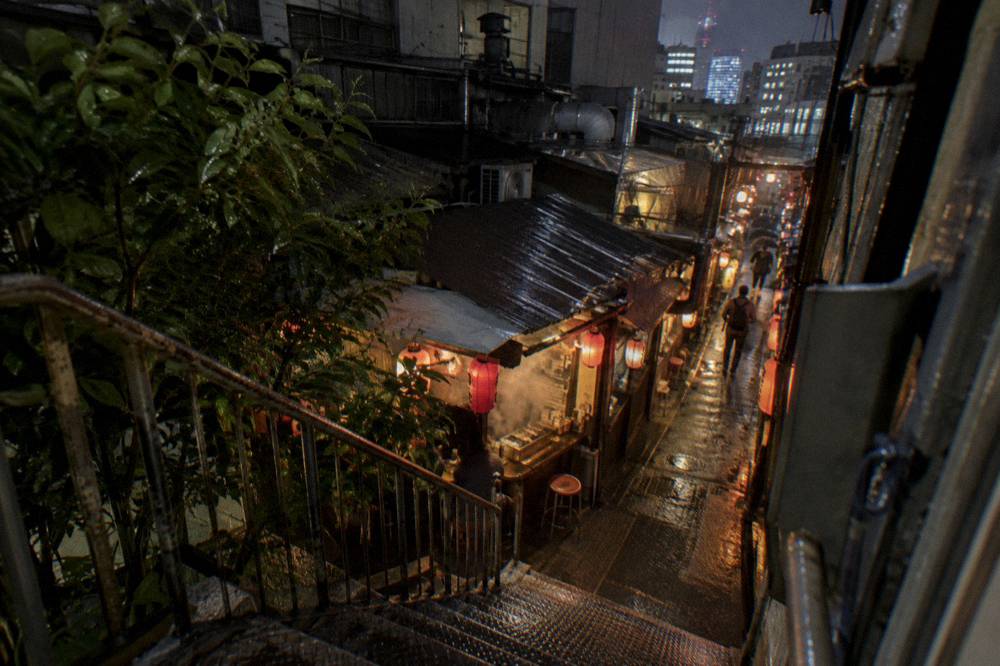 Neon signs and lanterns above a narrow Shinjuku drinking alley at night