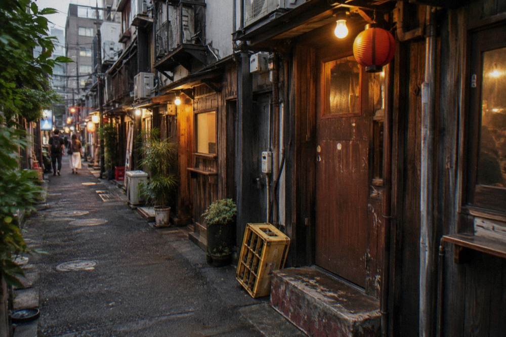 Row of small glowing bar entrances along a Golden Gai alley in the evening