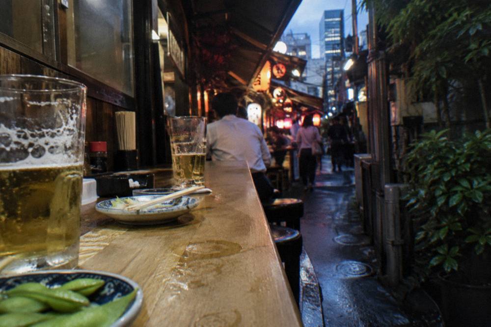 Small plates and glasses of beer arranged on a wooden izakaya counter