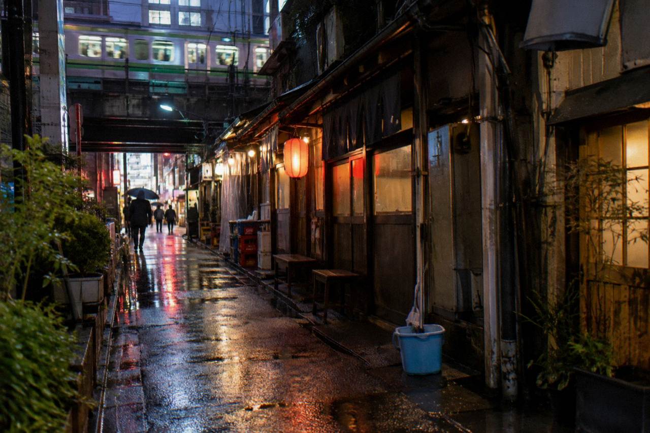 Neon signs glowing over a narrow alley of small restaurants in Shibuya at night