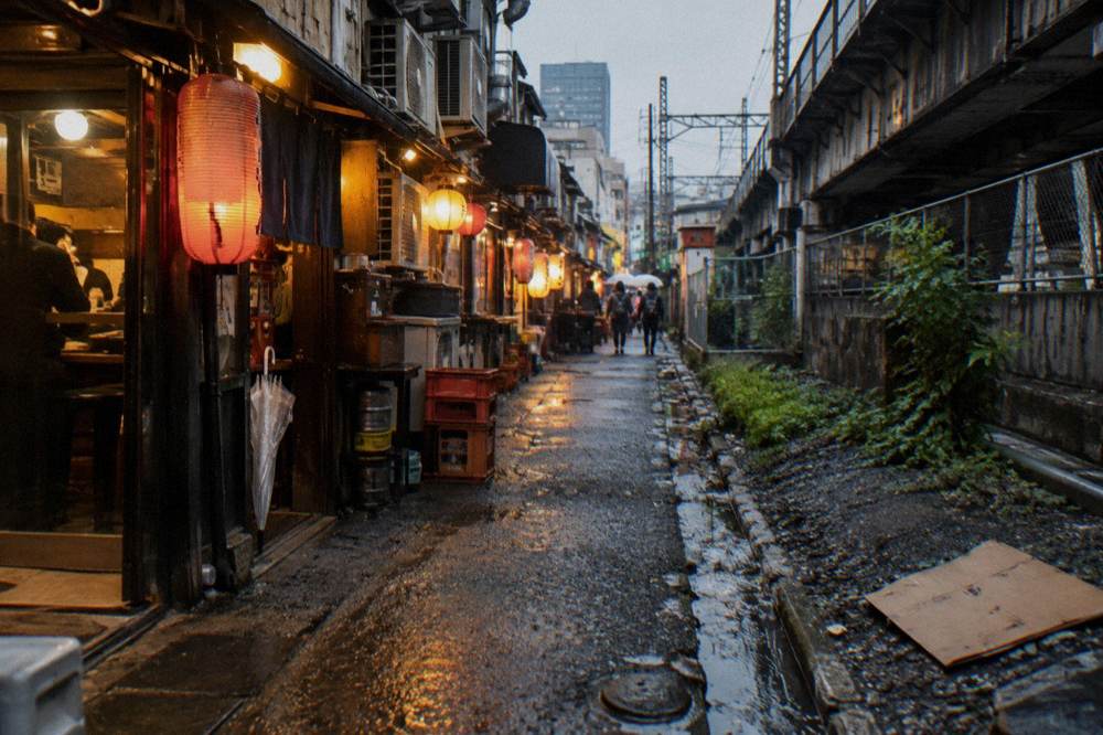 Row of small glowing restaurant entrances lining a narrow pedestrian lane