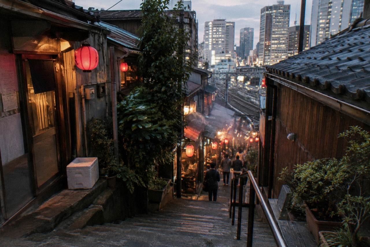 Narrow lantern-lit alley in Shinjuku at dusk with small restaurant signs glowing