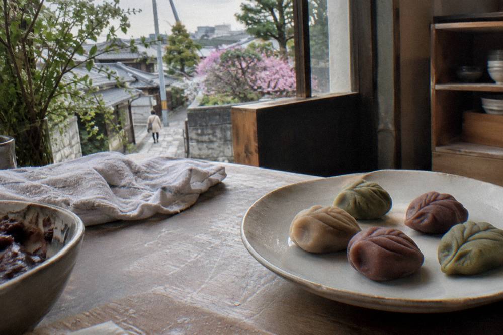 Colorful wagashi sweets shaped like leaves arranged on a ceramic plate in a cooking studio.