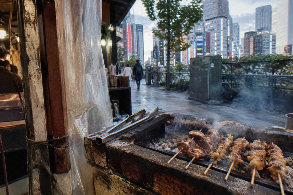 Grilled yakitori skewers resting on a smoky izakaya grill