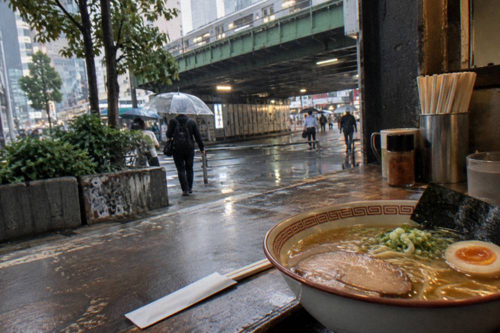 A steaming bowl of homemade ramen topped with chashu pork, egg and scallions on a restaurant counter
