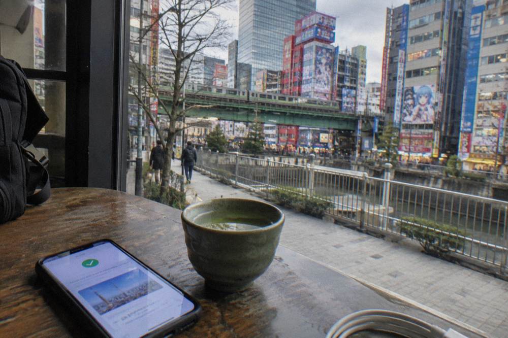 Smartphone showing a restaurant booking confirmation beside a cup of tea on a wooden table