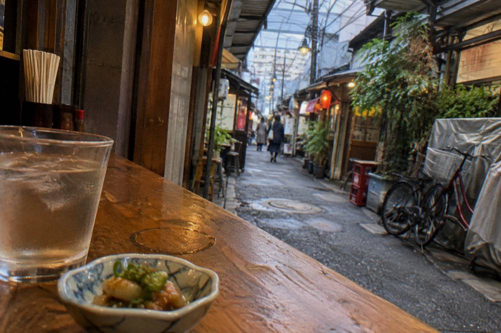 Small otoshi appetizer dish and a glass on a wooden izakaya counter